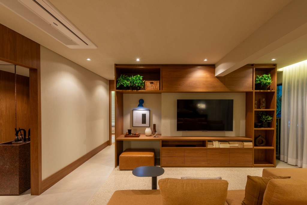Cores vivas marcam apês de 64 e 85 m² assinados por Todos Arquitetura. Na foto, sala de estar com estante para TV e plantas.