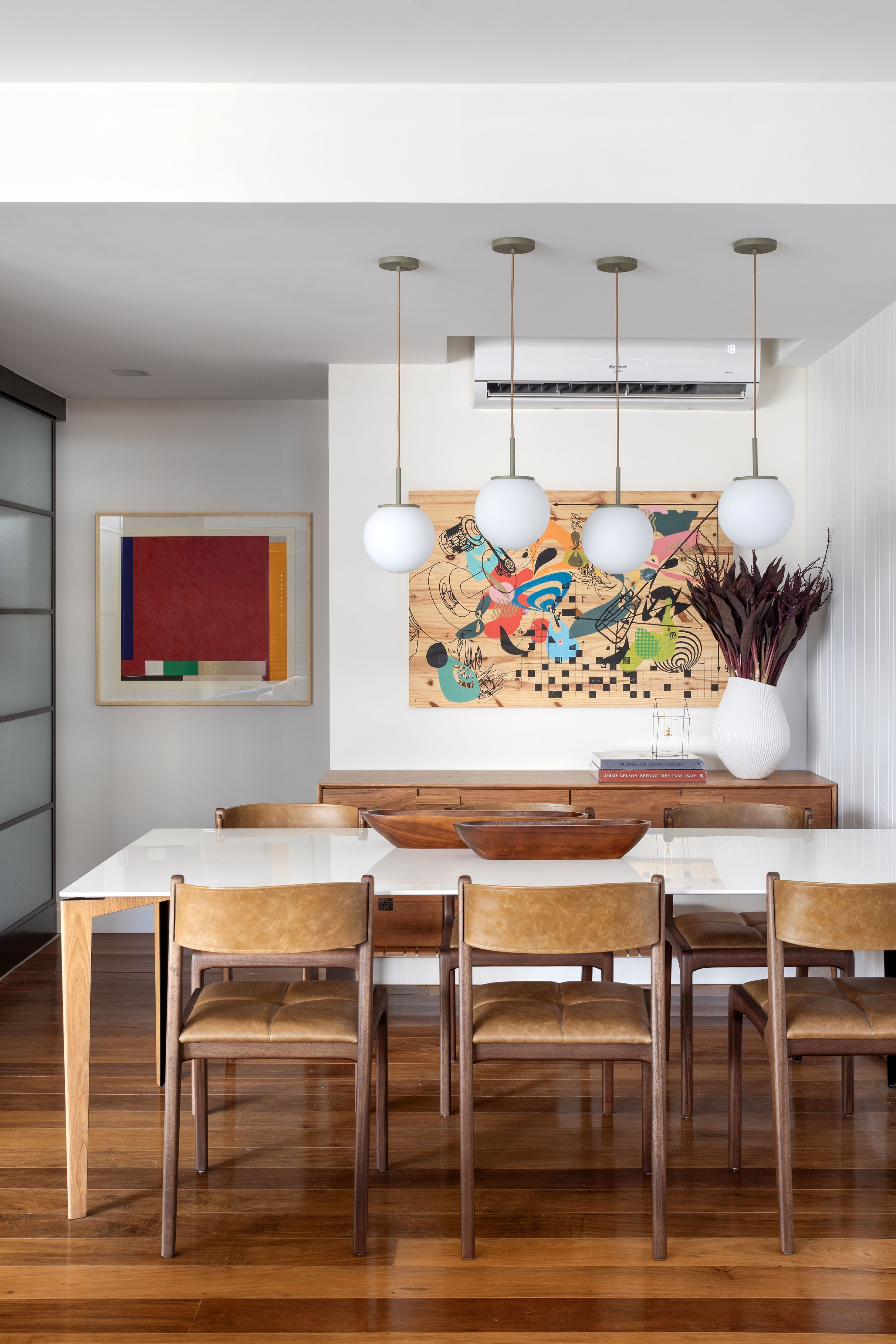 Estante com 50 nichos rouba a cena em sala de estar de apê de 150m². Projeto de Henrique Ramalho. Na foto, sala de jantar com mesa de tampo branco e luminárias esféricas.