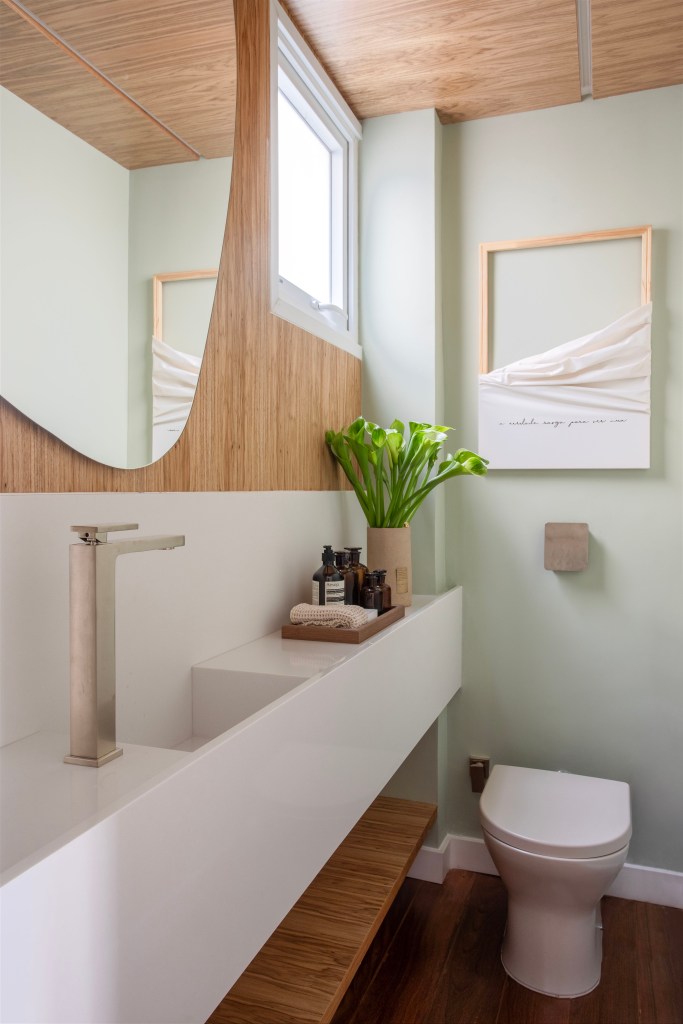 Estante com 50 nichos rouba a cena em sala de estar de apê de 150m². Projeto de Henrique Ramalho. Na foto, lavabo com parede verde clara, cuba esculpida e espelho em formato orgânico.