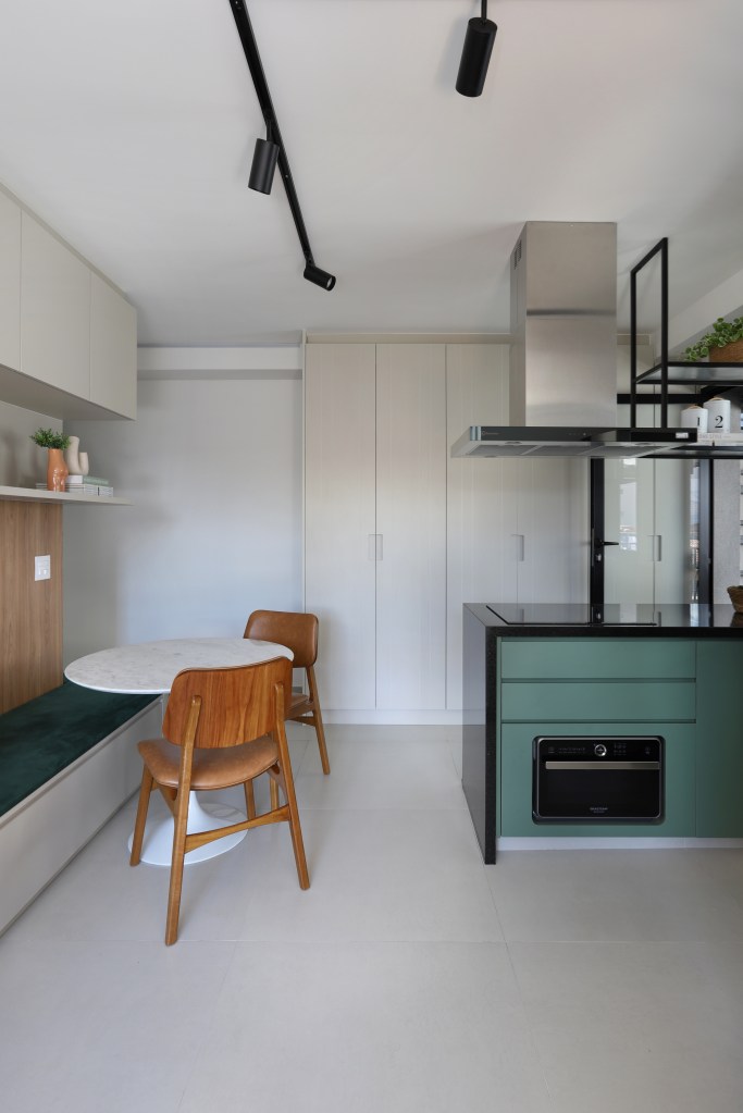 Marcenaria inteligente dá funcionalidade à apê de 42m² com área externa. Projeto de Fantato Nitoli Arquitetura. Na foto, sala pequena integrada com cozinha, marcenaria verde e banco fixo com estofado verde.