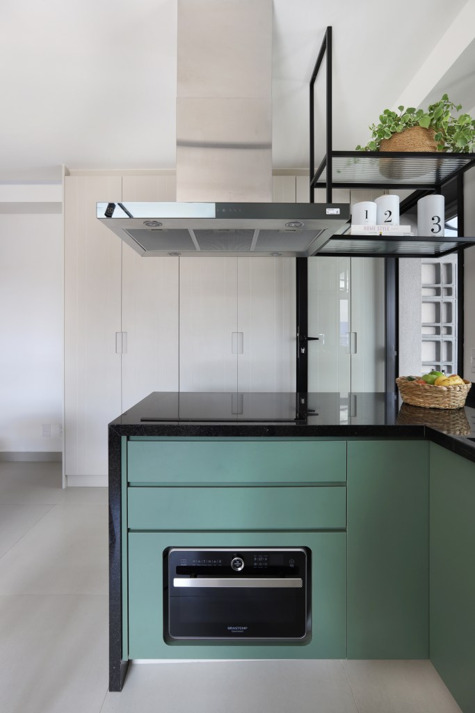 Marcenaria inteligente dá funcionalidade à apê de 42m² com área externa. Projeto de Fantato Nitoli Arquitetura. Na foto, cozinha pequena com marcenaria verde e bancada preta.