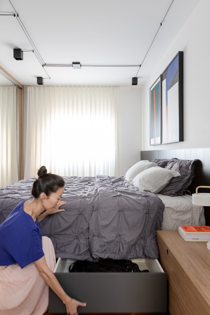 Painel e rack de TV separam living de home office em apê de 75m². Projeto de ISE Arquitetura. Na foto, quarto com cama de marcenaria e gaveta embutida.