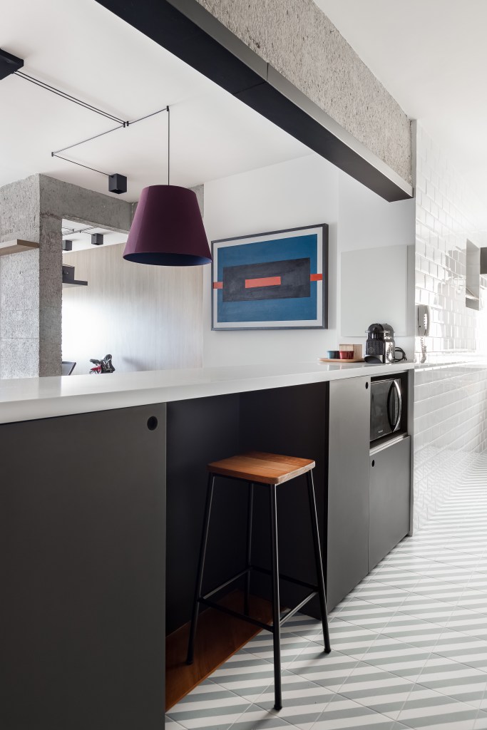 Painel e rack de TV separam living de home office em apê de 75m². Projeto de ISE Arquitetura. Na foto, cozinha com bancada e espaço para bancada.
