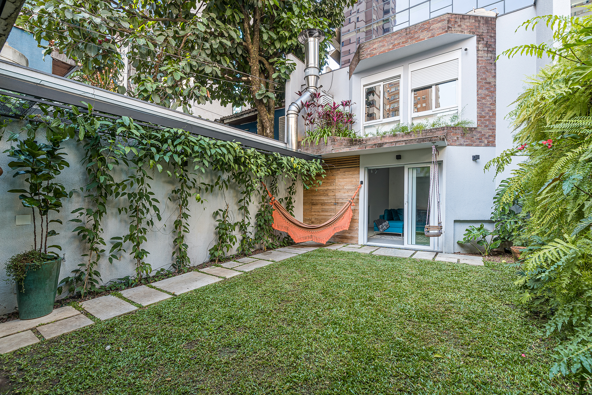 Em São Paulo, casa de vila vira óasis particular com jardim exuberante. Projeto de Marcela Fazio. Na foto, quintal, edicula, rede e jardim vertical.