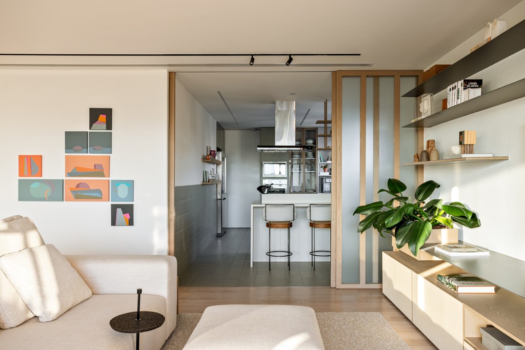 Superfícies de madeira e vidro e paredes brancas marcam apê de 350 m². Projeto do Studio AG. Na foto, cozinha separada por porta translúcida de correr.
