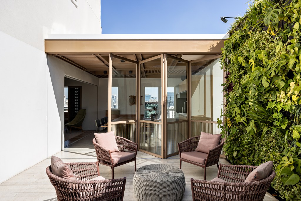 Superfícies de madeira e vidro e paredes brancas marcam apê de 350 m². Projeto do Studio AG. Na foto, varanda com poltronas e jardim vertical.