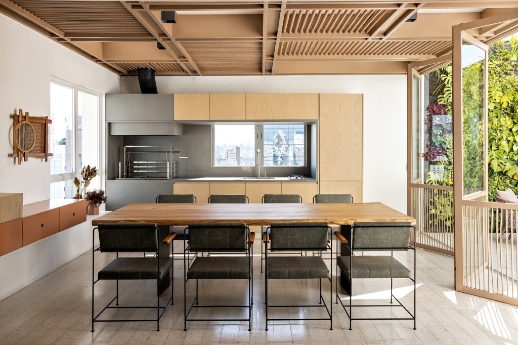 Superfícies de madeira e vidro e paredes brancas marcam apê de 350 m². Projeto do Studio AG. Na foto, cozinha e churrasqueira com bancada e vista para a varanda.