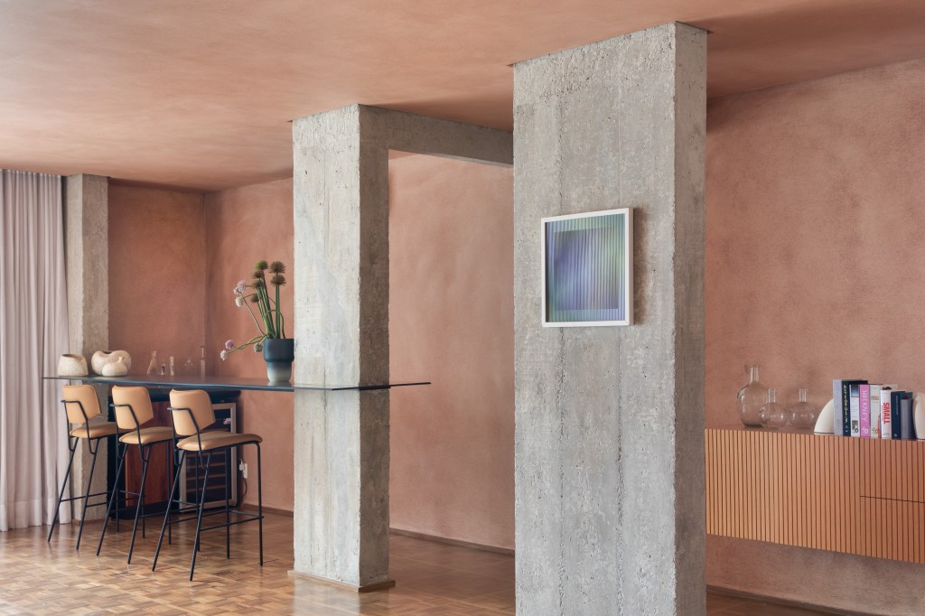 Textura terrosa nas paredes marca o décor deste apê de 220 m². Projeto de Navarro Arquitetura. Na foto, copa com bar e colunas de concreto.