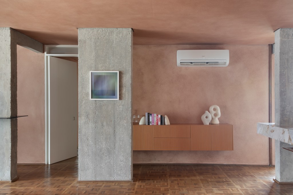 Textura terrosa nas paredes marca o décor deste apê de 220 m². Projeto de Navarro Arquitetura. Na foto, sala com aparador, coluna de concreto e parede terrosa.