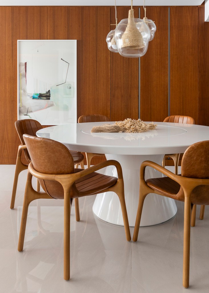 Varanda generosa com vista para o mar é destaque em apê de 160m². Projeto de SUM + Studio. Na foto, sala de jantar com mesa redonda branca grande.
