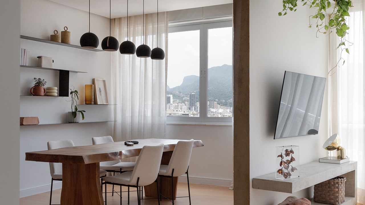 Vigas, reboco aparente e texturas artesanais marcam este apê de 130 m². Projeto de Mariana Monnerat. Na foto, sala de jantar com parede texturizada, sala de Tv e plantas.