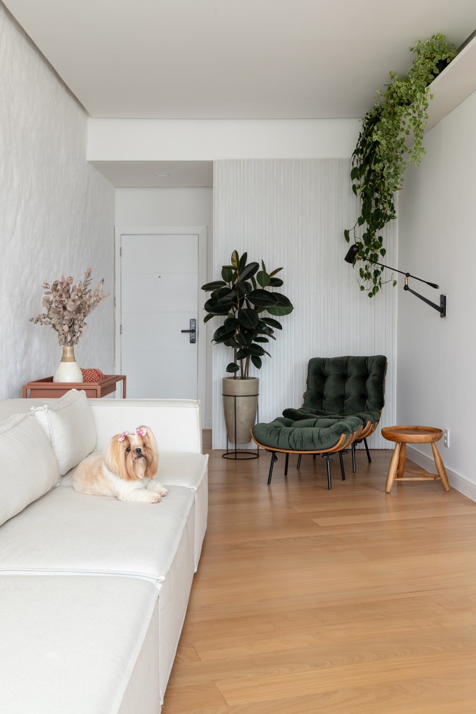 Vigas, reboco aparente e texturas artesanais marcam este apê de 130 m². Projeto de Mariana Monnerat. Na foto, sala de estar com parede texturizada e sofá branco.