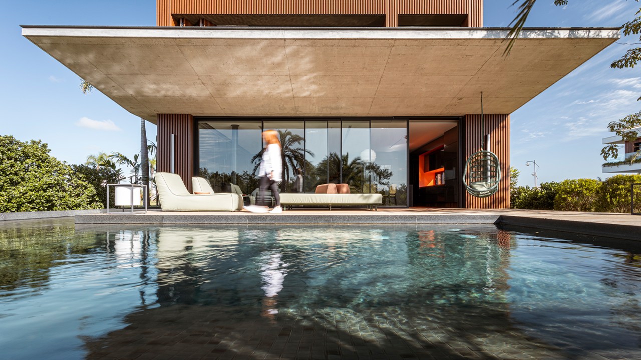 A água é destaque nesta casa de 457 m² no Rio Grande do Sul. Projeto de Stemmer Rodrigues. Na foto, fachada com jardim e piscina.