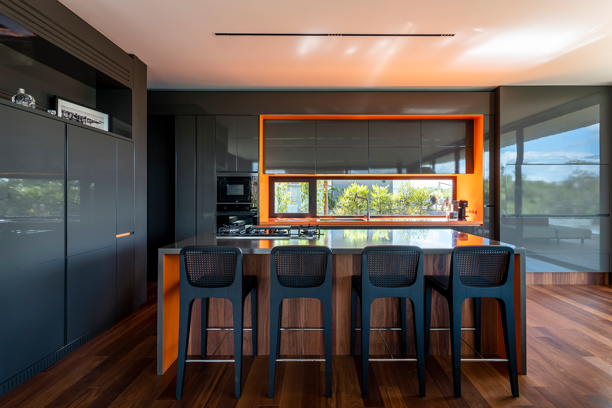 A água é destaque nesta casa de 457 m² no Rio Grande do Sul. Projeto de Stemmer Rodrigues. Na foto, cozinha com revestimentos laranja e cinza.