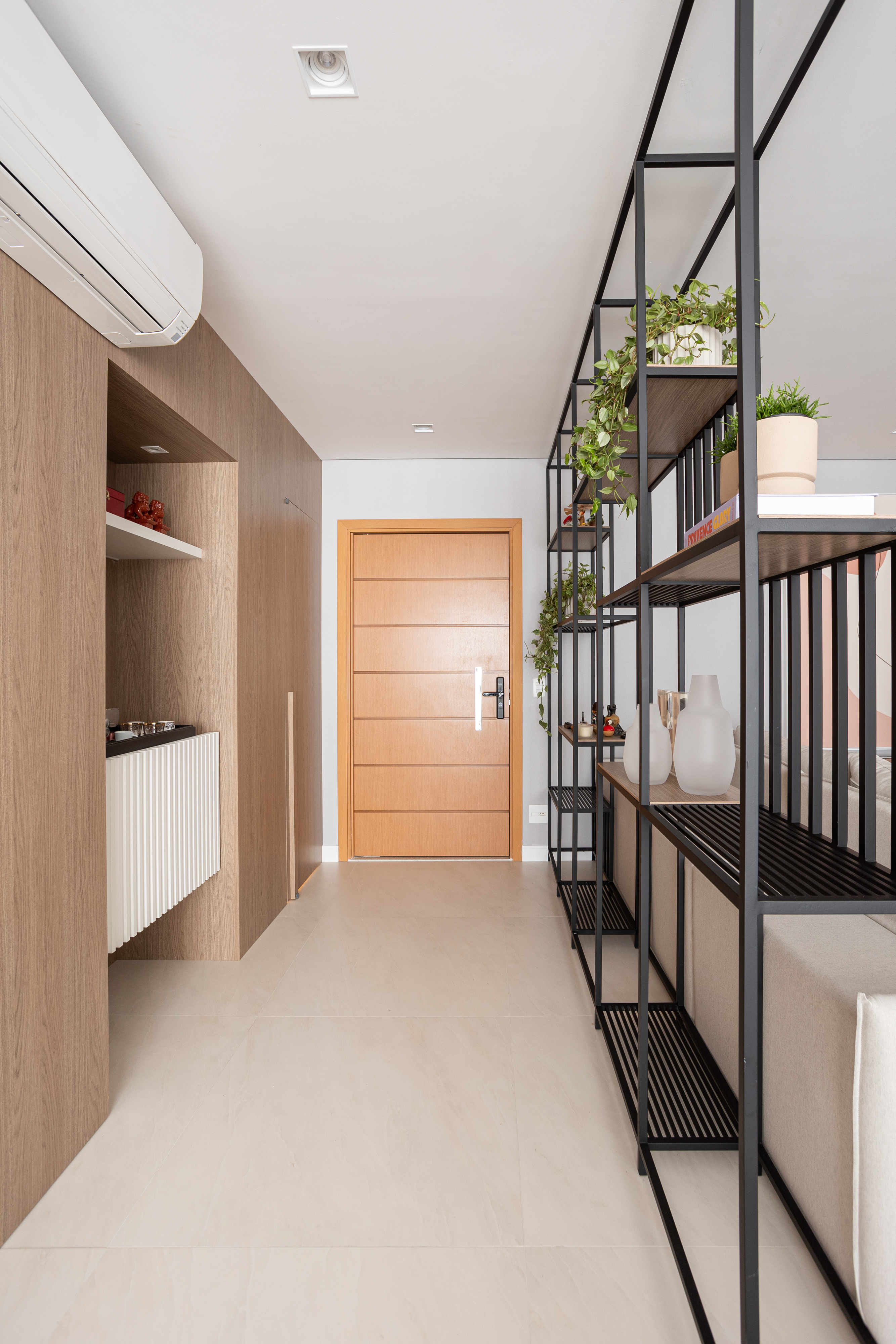 Apartamento de 140 m² possui parede de pedra moledo e quarto montessoriano. Projeto Loft 7 Arquitetura. Na foto, hall de entrada com estante de serralheira e canto do café.