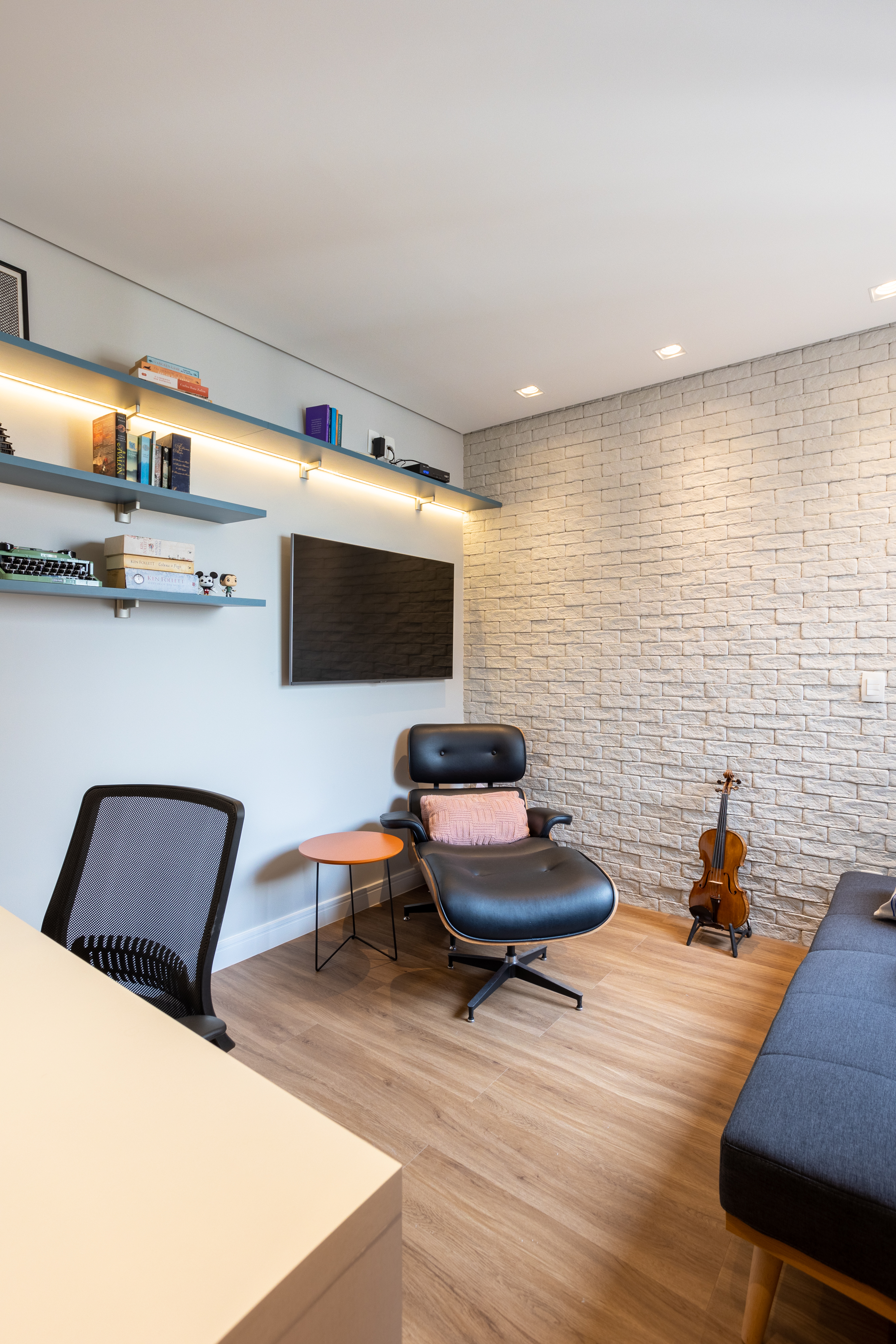 Apartamento de 140 m² possui parede de pedra moledo e quarto montessoriano. Projeto Loft 7 Arquitetura. Na foto, home office com parede de tijolinhos e sofá-cama.
