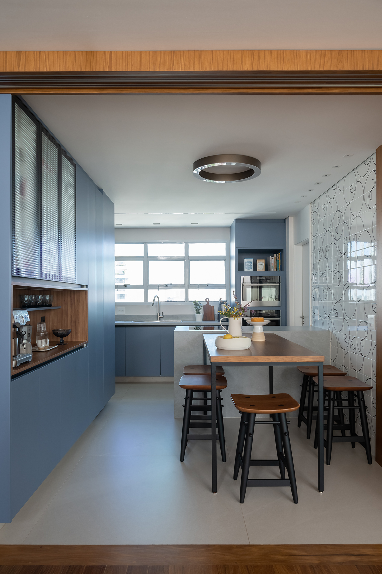 Apartamento de 188 m² ganha dois cooktops na cozinha e balanços na sala, Projeto Raízes Arquitetos. Na foto, cozinha com marcenaria azul e ilha. Cooktop e nicho para café.