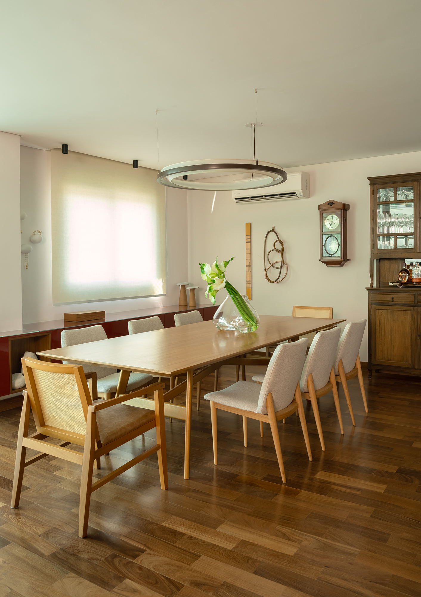 Apartamento de 188 m² ganha dois cooktops na cozinha e balanços na sala, Projeto Raízes Arquitetos. Na foto, sala de jantar com cristaleira e relógio antigo.