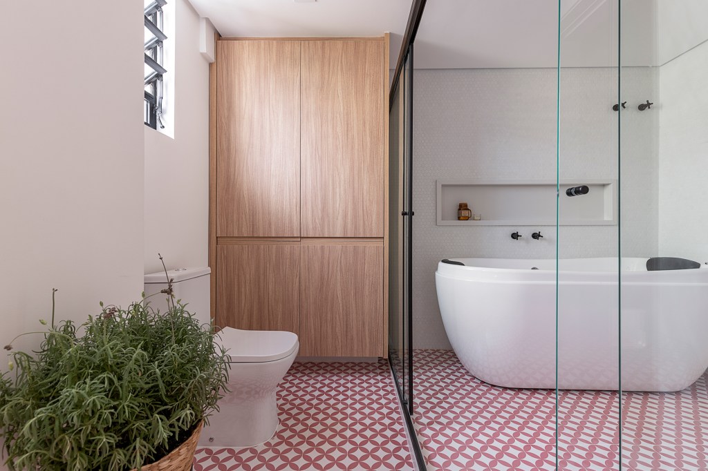 Apartamento dos anos 1950 une charme, história e cores em 128 m². Projeto de Ju Matos Arquitetura. Na foto, banheiro com banheira de apoio e piso geométrico vermelho.