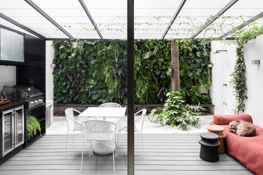 Apartamento garden de 100 m² mescla materiais para criar um ar industrial. Projeto de Nati Minas. Na foto, varanda externa com jardim vertical e churrasqueira.