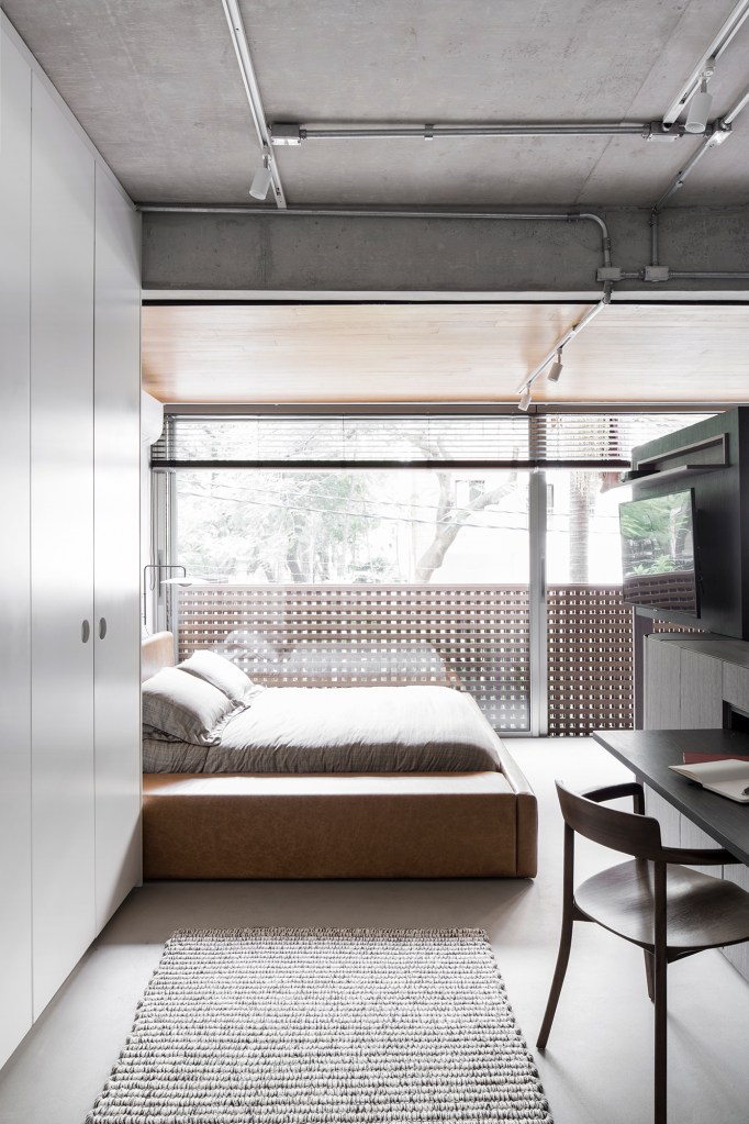 Apartamento garden de 100 m² mescla materiais para criar um ar industrial. Projeto de Nati Minas. Na foto, quarto de casal com cabeceira de couro.