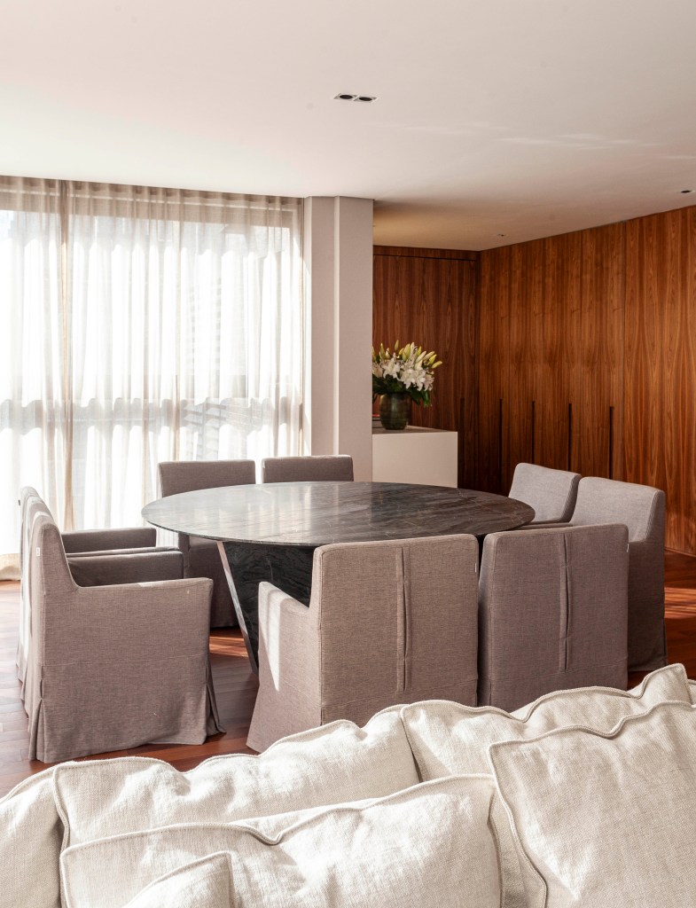 Apê de 174 m² tem decoração clássica e sofisticada com tons neutros. Projeto de David Bastos. Na foto, sala de jantar com mesa redonda e cadeiras.