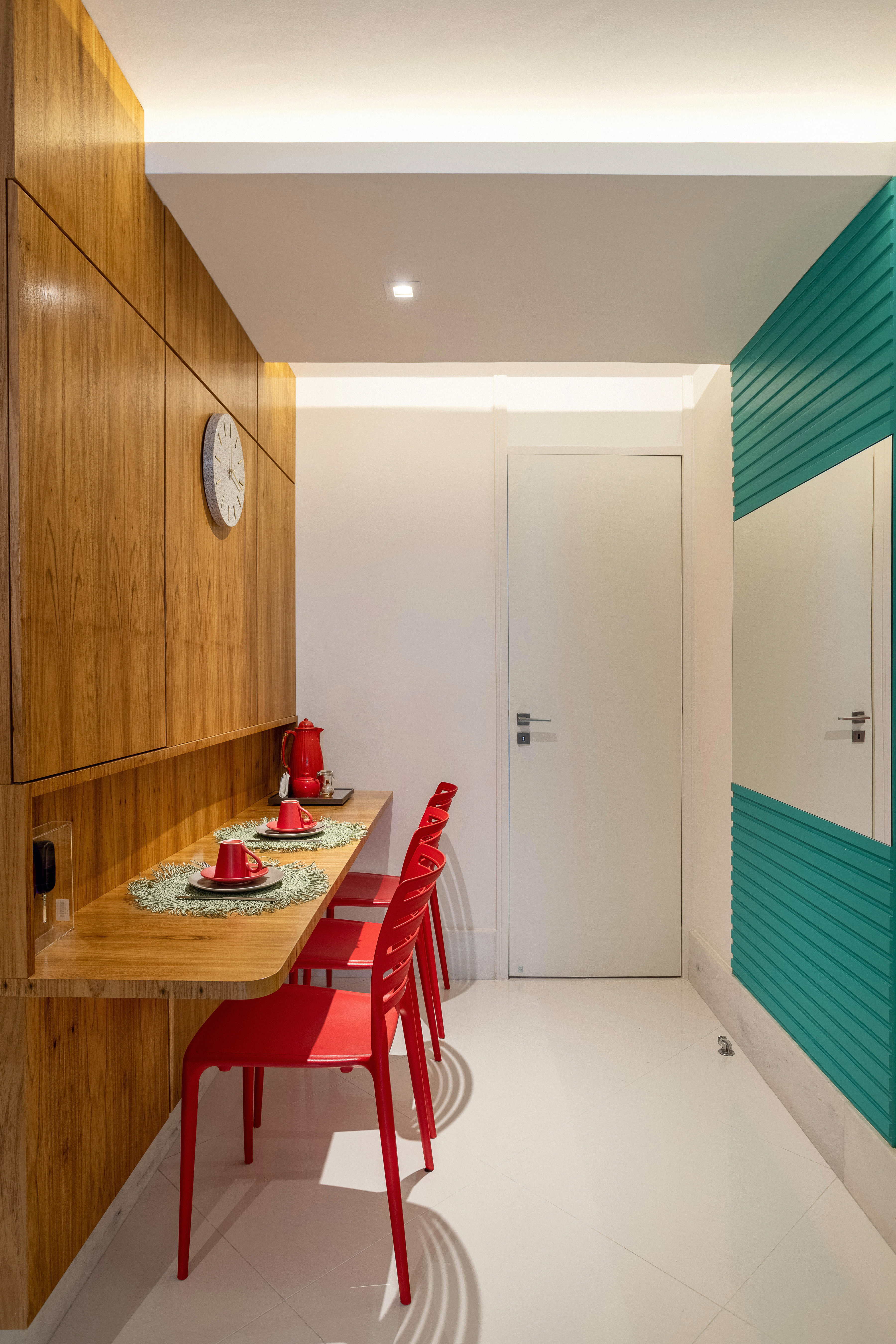 Apê ganha mezanino com home office, lavabo azul e copa de cozinha turquesa. Projeto de Ana Cano Arquitetura. Na foto, copa de cozinha com painel turquesa, parede revestida de madeira, cadeiras vermelhas.