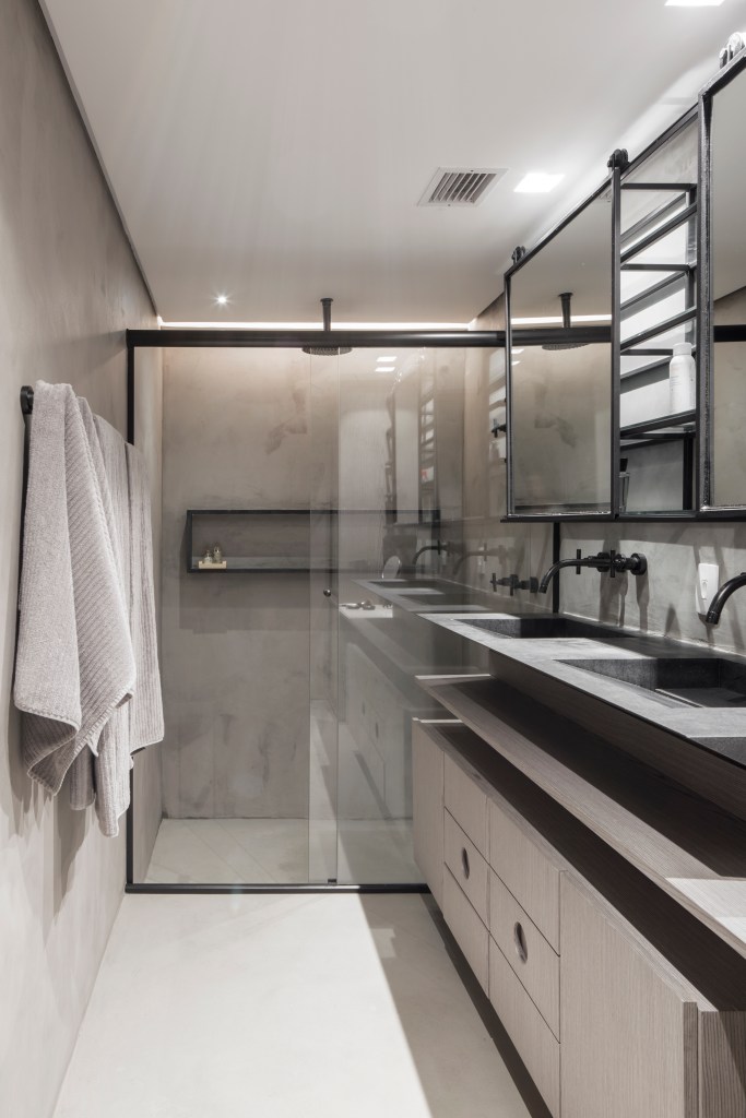 Apê térreo preto e branco tem áreas sociais e de trabalho mescladas. Projeto de Nati Minas & Studio. Na foto, banheiro com duas cubas soltas pretas.