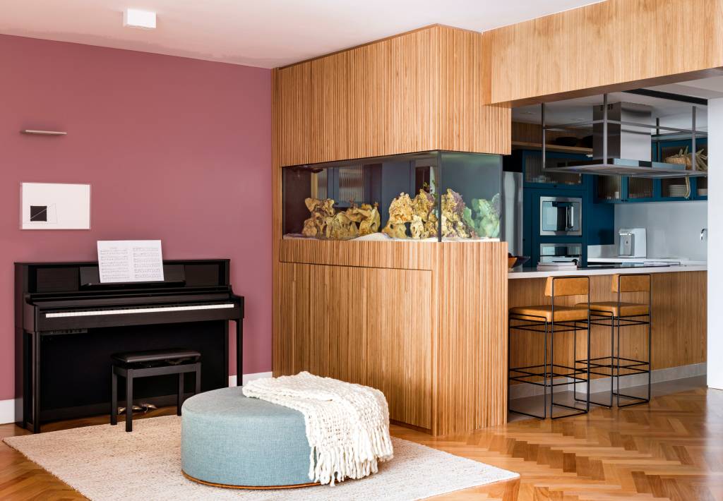 Aquário de peixes funciona como divisória entre sala e cozinha neste apê