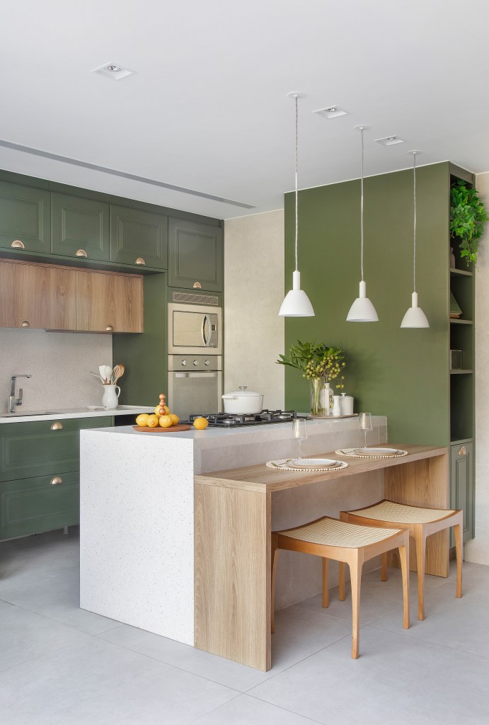 Casa de 300 m² tem cozinha verde oliva e área gourmet em contêiner. Projeto de Lana Rocha. Na foto, cozinha com ilha e bancada e armários verde oliva.