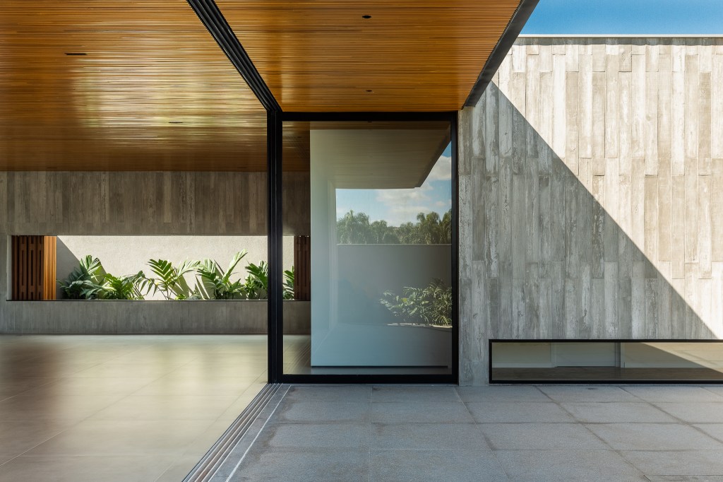 Casa de 379 m² une arquitetura minimalista e integração com o entorno. Projeto Camila Porto. Na foto, varanda gourmet com vista para o jardim.
