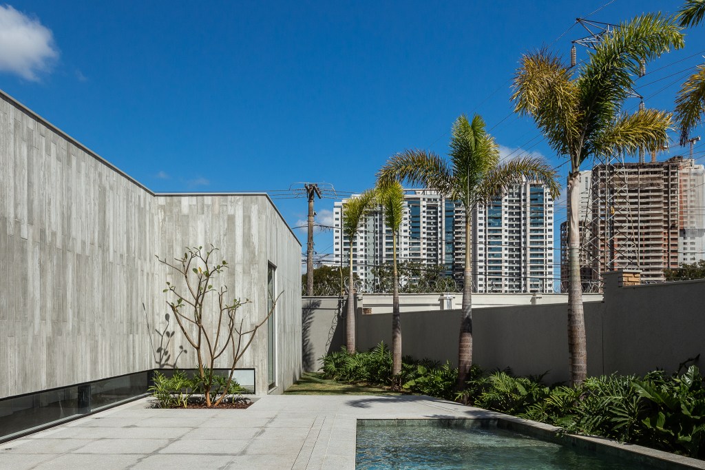 Casa de 379 m² une arquitetura minimalista e integração com o entorno. Projeto Camila Porto. Na foto, fachada com jardim e piscina.