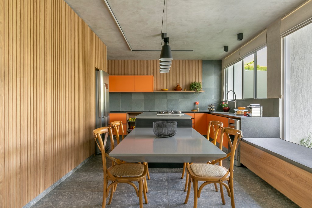 Casa ganha área gourmet e cozinha com marceneira laranja e ardósia. Projeto de Morada 3112 Arquitetura. Na foto, cozinha, ardósia, armários laranja, armários ripados.