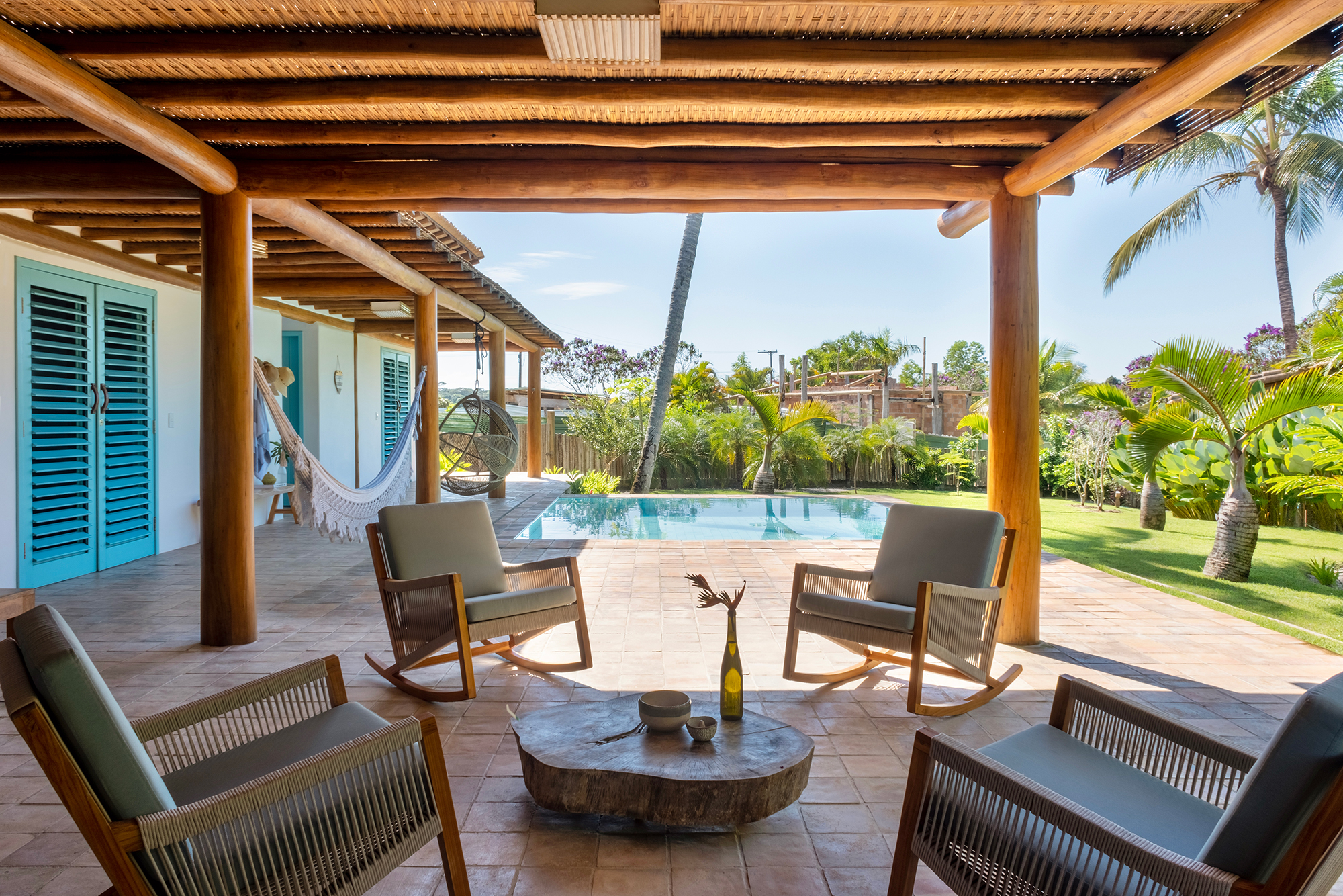 Casa em Trancoso é inspirada na arquitetura colonial do sul da Bahia. Projeto Conrado Ceravolo. Na foto, piscina com poltrona suspensa e banco. Varanda com pergolado.