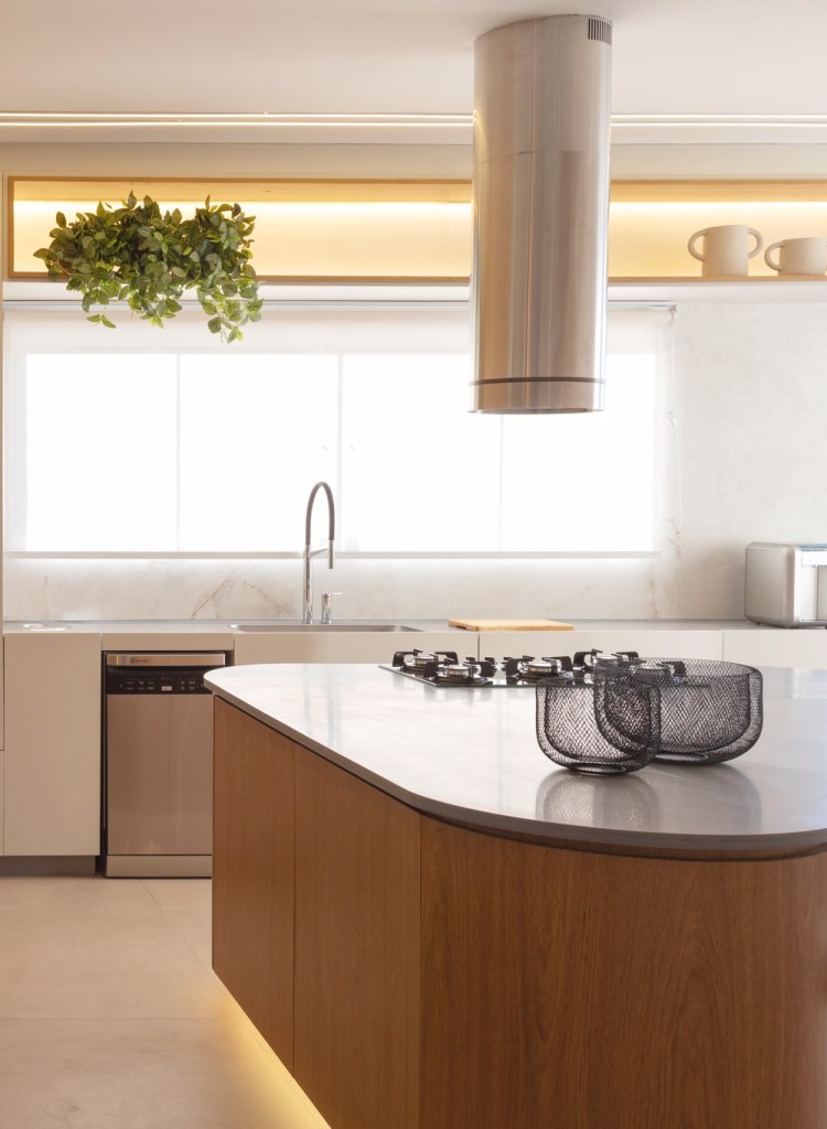 Casa do zagueiro da seleção Gleison Bremer tem estilo minimalista elegante. Projeto de Daniel Santana. Na foto, cozinha minimalista com ilha em formato orgânico, painéis de madeira.