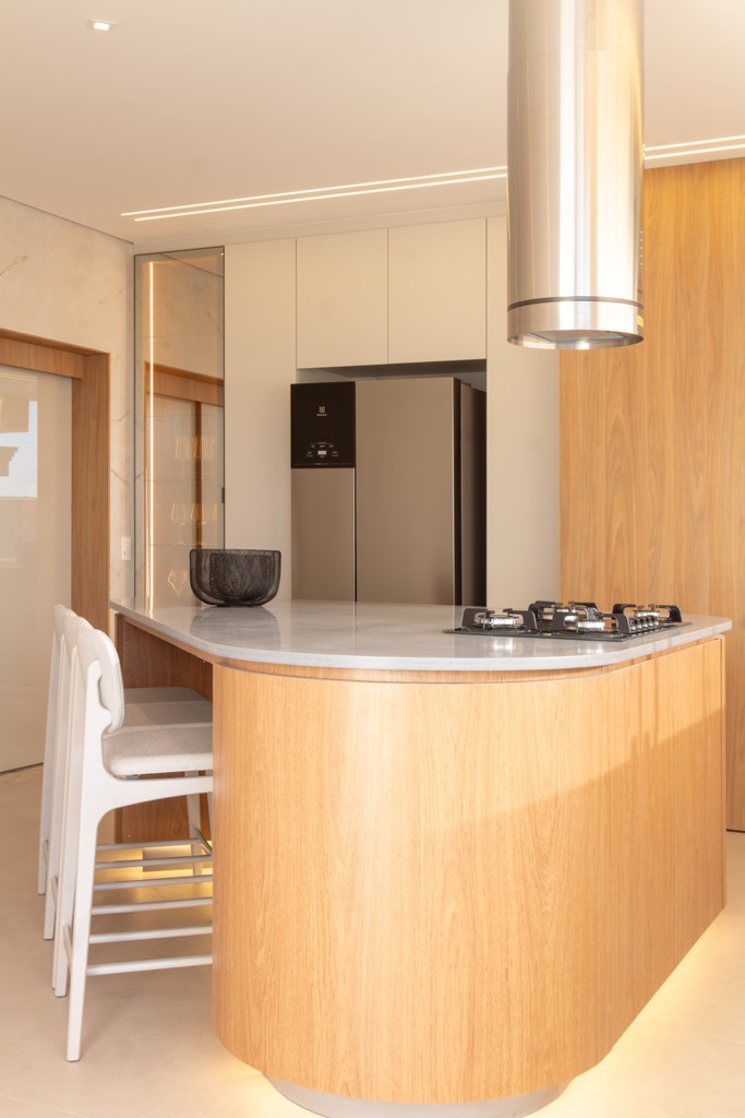 Casa do zagueiro da seleção Gleison Bremer tem estilo minimalista elegante. Projeto de Daniel Santana. Na foto, cozinha minimalista com ilha em formato orgânico, painéis de madeira.