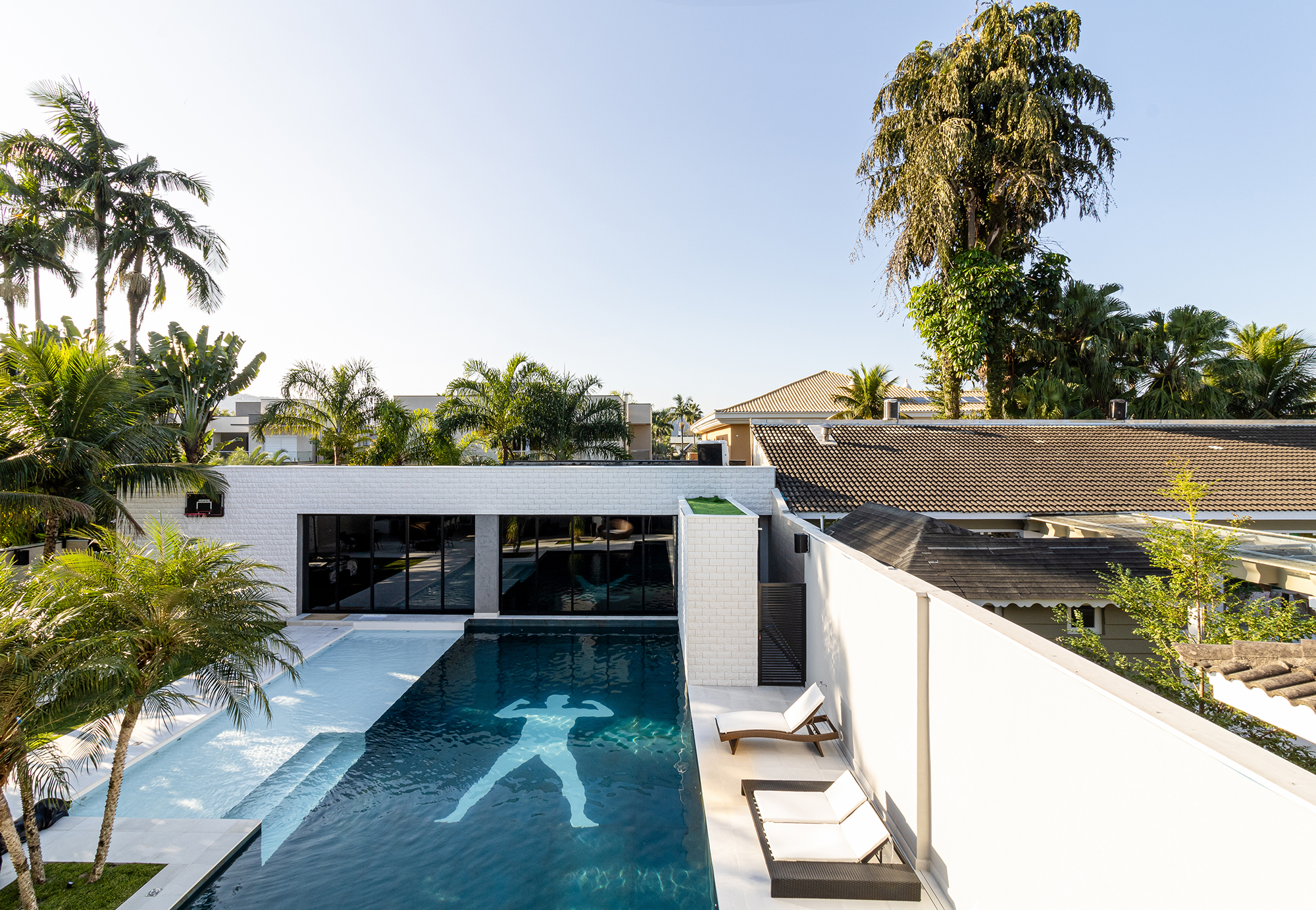 Conheça a mansão no Guarujá do jogador Gabigol. Projeto de Carlos Pardal Arquitetura. Na foto, fachada com piscina e jardim.