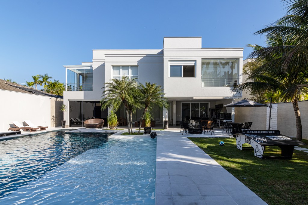 Conheça a mansão no Guarujá do jogador Gabigol. Projeto de Carlos Pardal Arquitetura. Na foto, fachada com piscina e jardim.