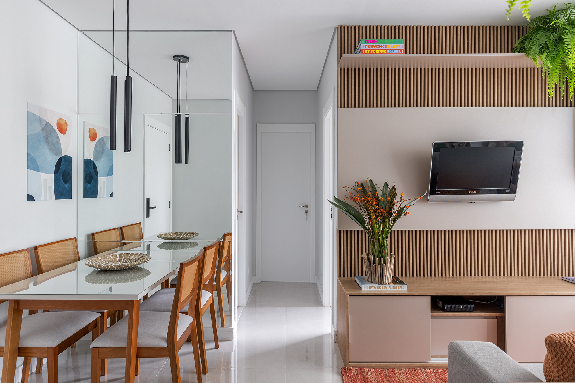 Cozinha verde e granilite no banheiro marca apartamento de 58 m². Projeto de Pixel Arquitetura. Na foto, sala de jantar com parede de espelho e painel ripado para a TV.