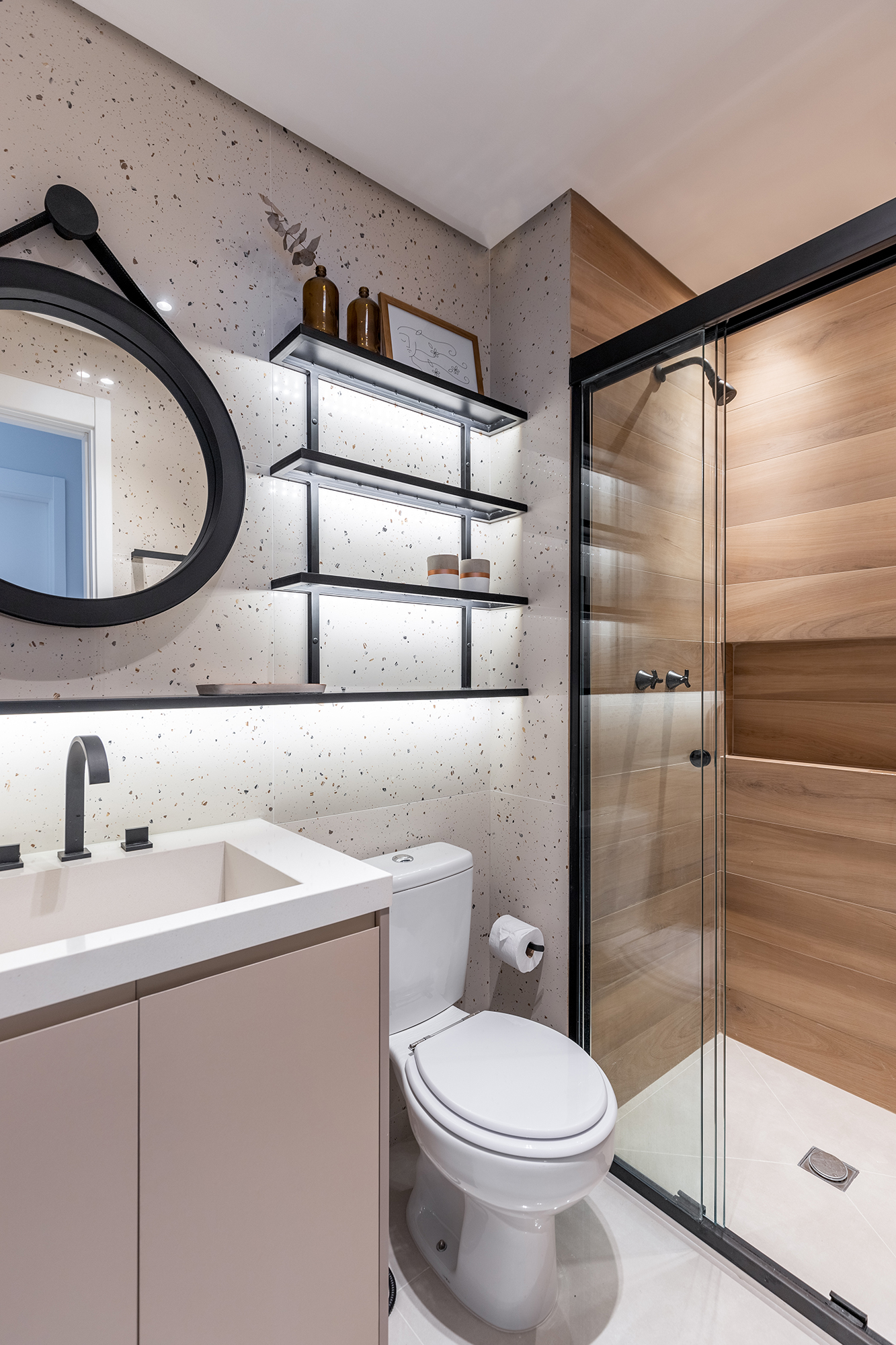Cozinha verde e granilite no banheiro marca apartamento de 58 m². Projeto de Pixel Arquitetura. Na foto, banheiro com boxe de serralheria e revestimentos de granilite e textura de madeira.