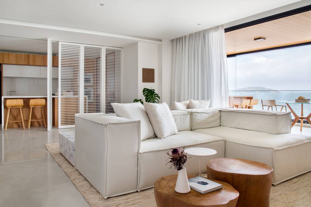 Décor essencial com branco e madeira peroba valoriza o mar neste apê