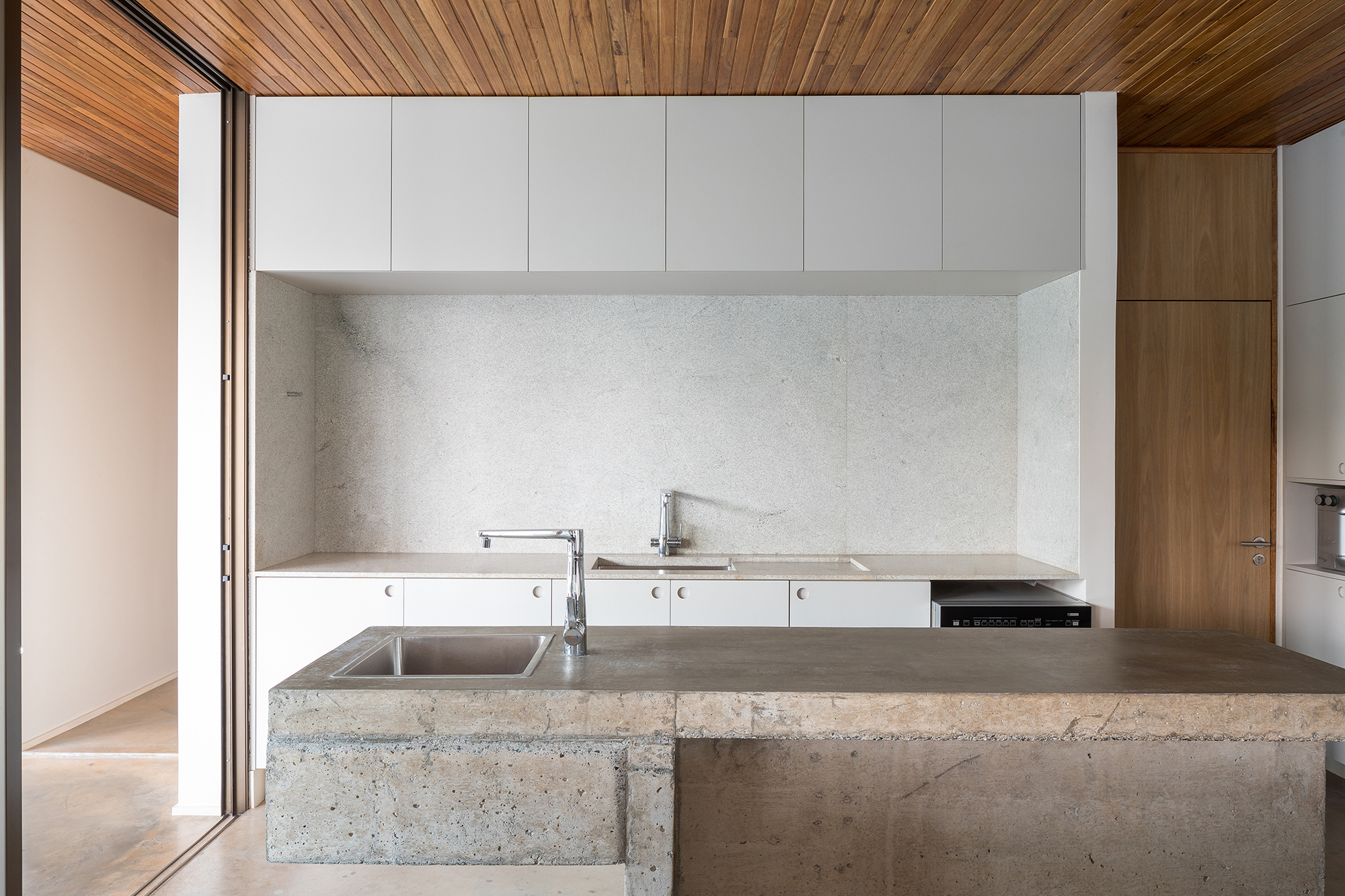 Dois volumes sobrepostos compõem esta casa de 500 m² em Brasília. Projeto de Bloco Arquitetos. Na foto, cozinha com bancada de concreto e armários.