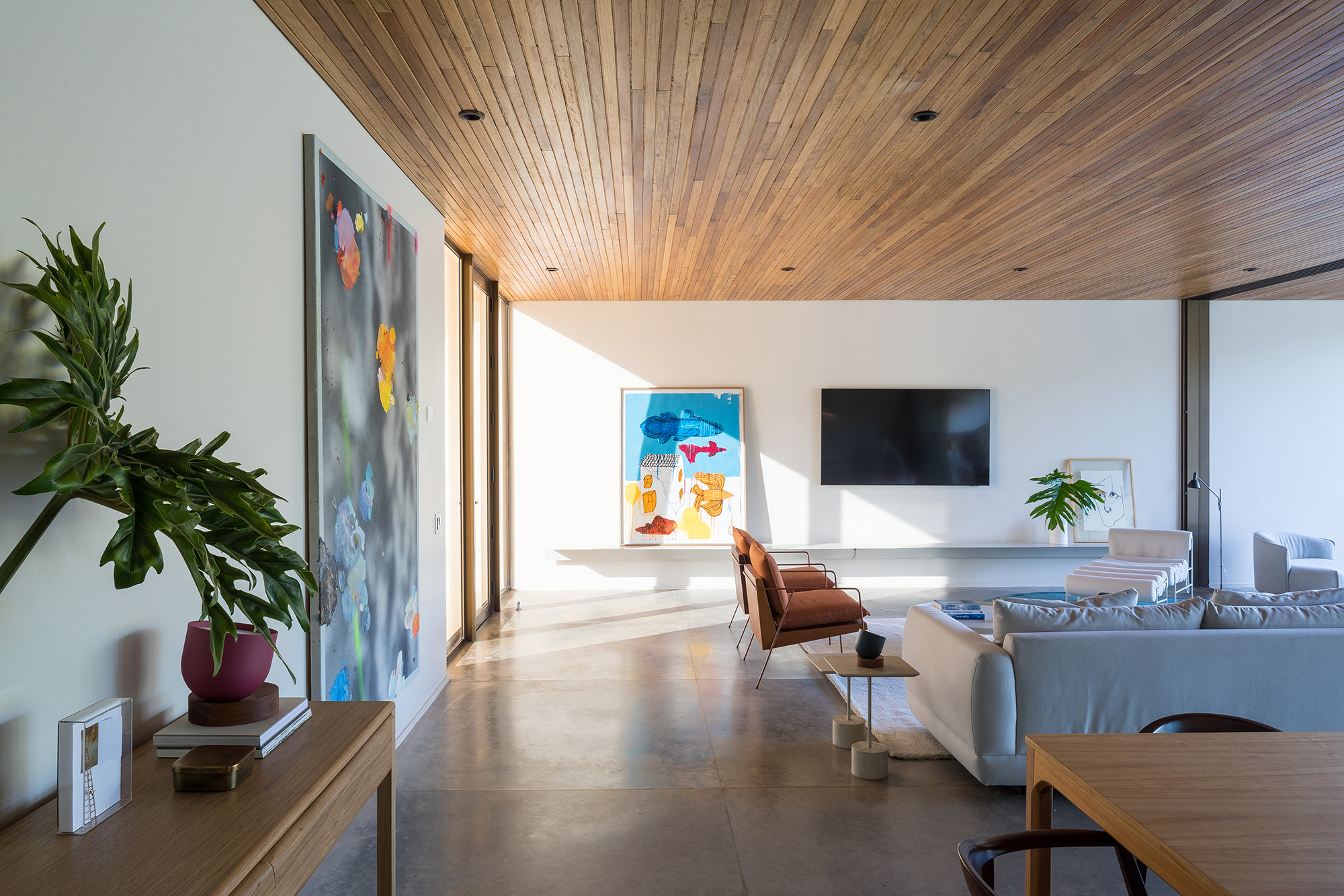 Dois volumes sobrepostos compõem esta casa de 500 m² em Brasília. Projeto de Bloco Arquitetos. Na foto, sala de tv com quadros e sofá.