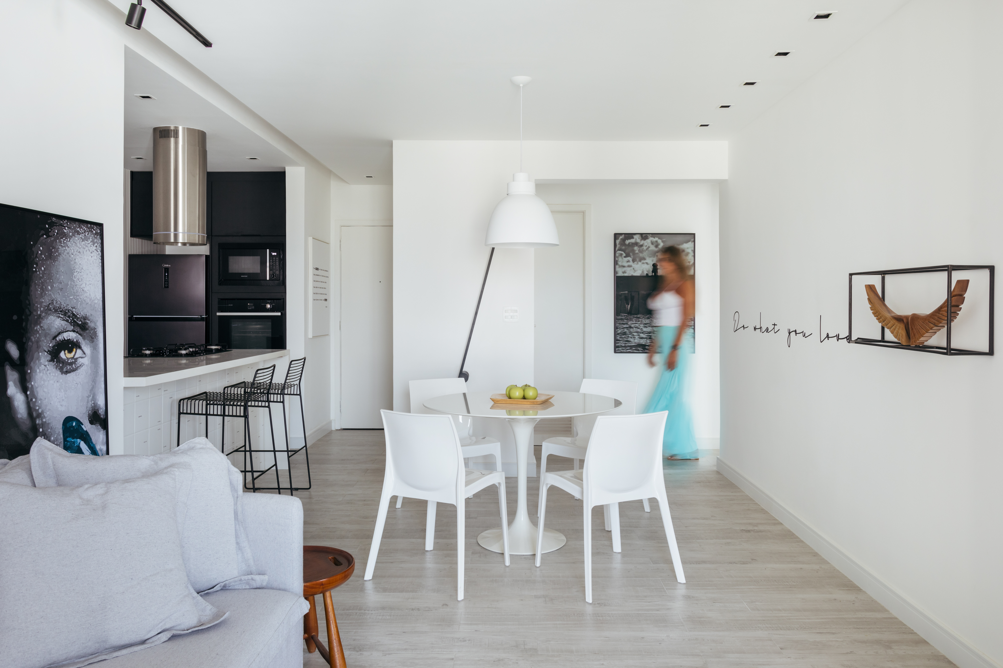 Estilo escandinavo inspira décor de apê de 84m² com paleta preta e branca. Projeto de Nilton Montarroyos. Na foto, sala de estar e jantar integradas com mesa branca, cadeira branca e luminária branca.