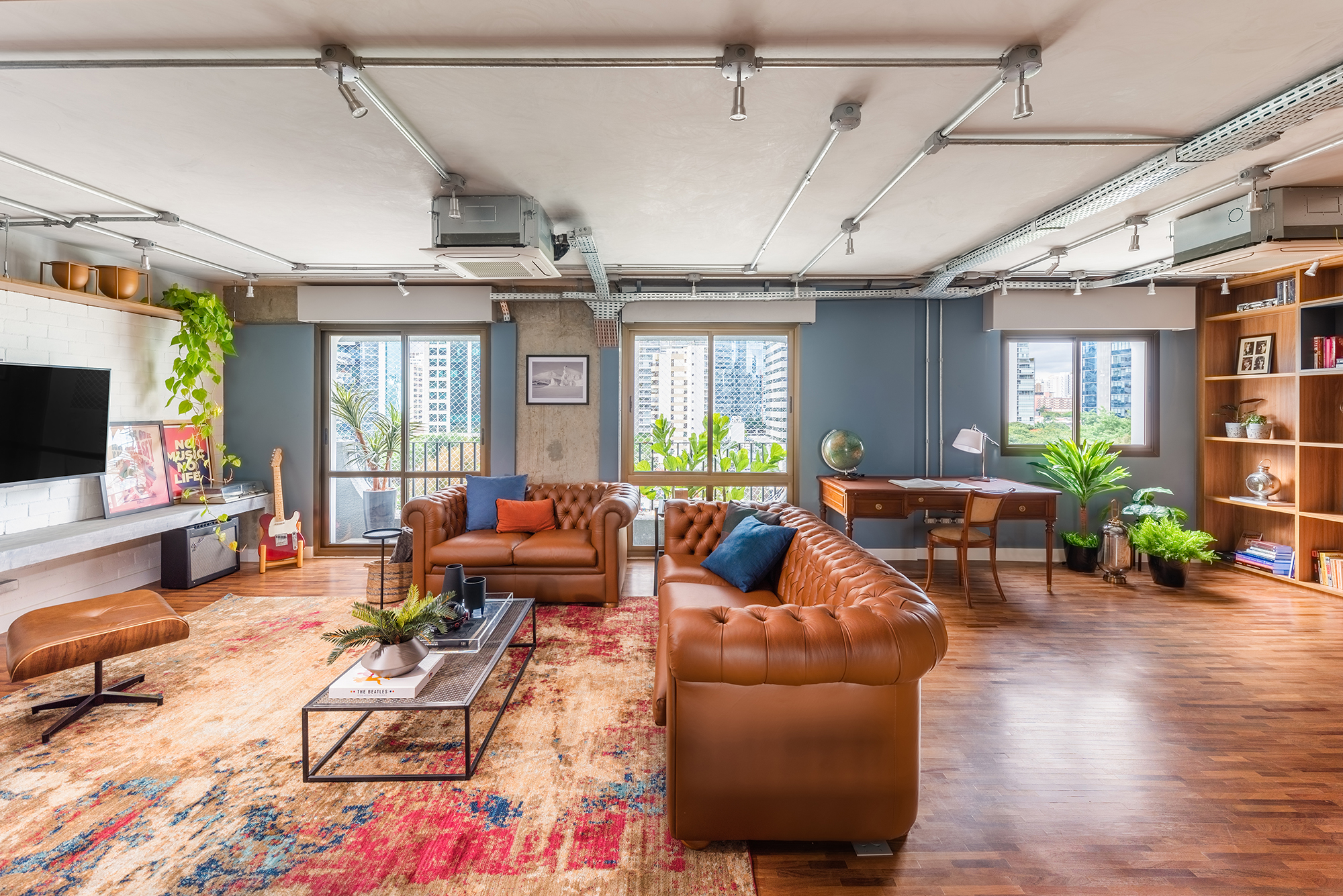 Estilo industrial e elementos clássicos se unem em apartamento de 130 m². Projeto de Pietro Terlizzi. Na foto, sala com tv, parede de tiles e sofá cheestfield.