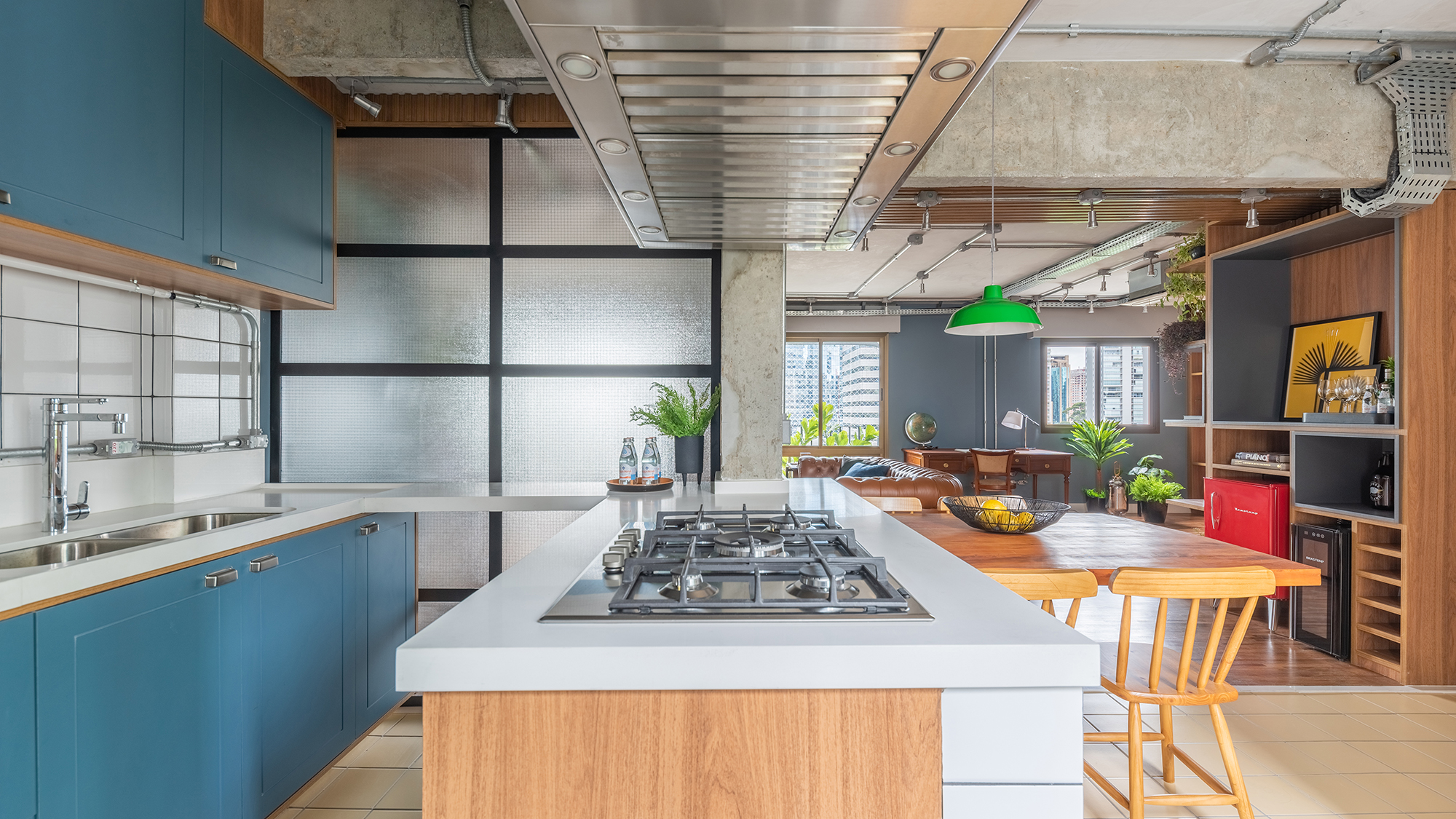 Estilo industrial e elementos clássicos se unem em apartamento de 130 m². Projeto de Pietro Terlizzi. Na foto, cozinha com marcenaria azul e tiles na parede. Sala de jantar integrada ao social.