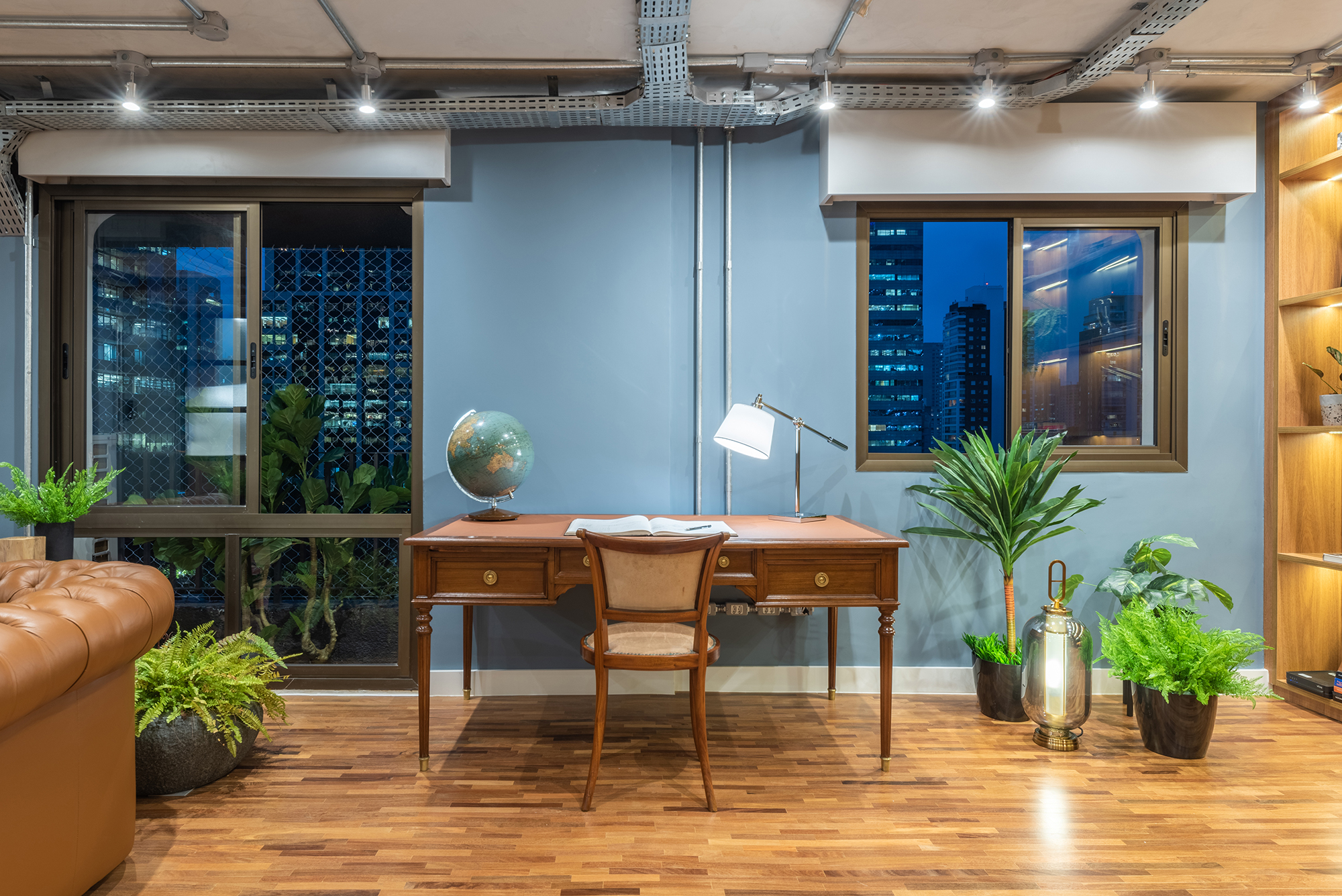 Estilo industrial e elementos clássicos se unem em apartamento de 130 m². Projeto de Pietro Terlizzi. Na foto, home office com parede azul e estante com iluminação indireta,