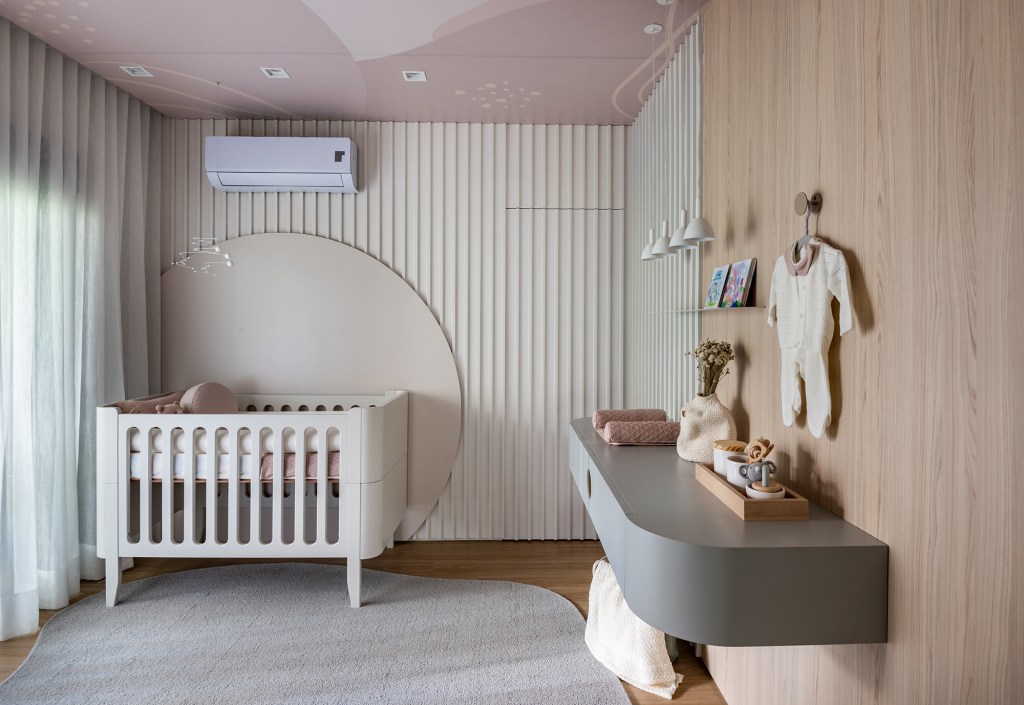 Formas orgânicas e tons neutros criam aconchego neste apê de 190 m². Projeto de Bohrer Arquitetos. Na foto, quarto de bebe com parede ripada e berço.