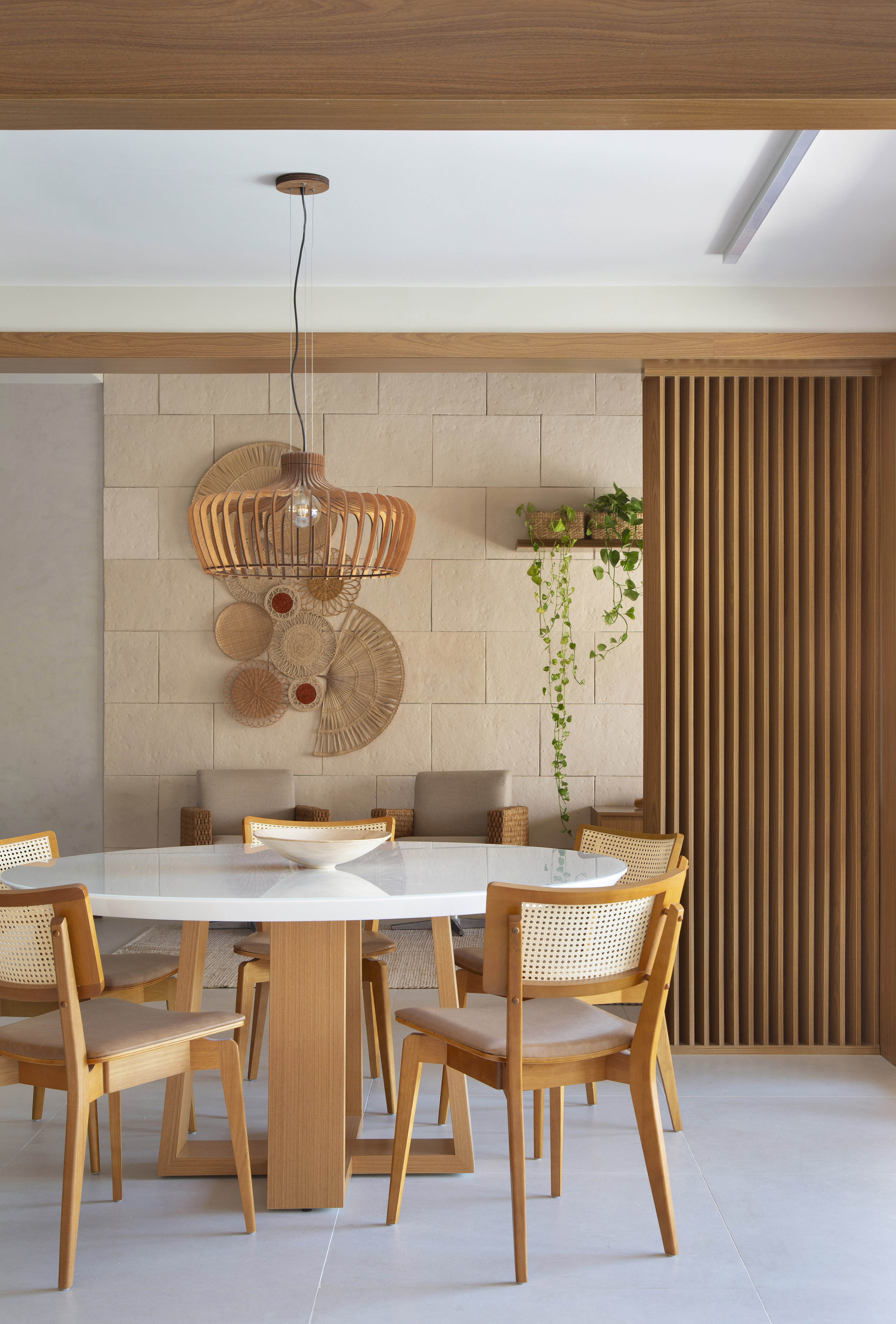 Ilha de cozinha revestida de azulejos com peixes é destaque nesta casa. Projeto de Travessa Arquitetura. Na foto, sala de estar, luminária de palhinha, mesa redonda de tampo branco.