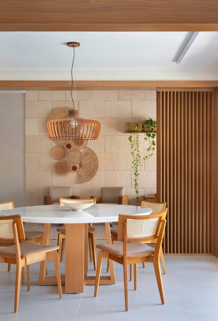 Ilha de cozinha revestida de azulejos com peixes é destaque nesta casa. Projeto de Travessa Arquitetura. Na foto, sala de estar, luminária de palhinha, mesa redonda de tampo branco.